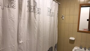 A bathroom with a shower curtain featuring The Beatles' name and a sink with a mirror. - Departamento Belgrano 6 (Salta)