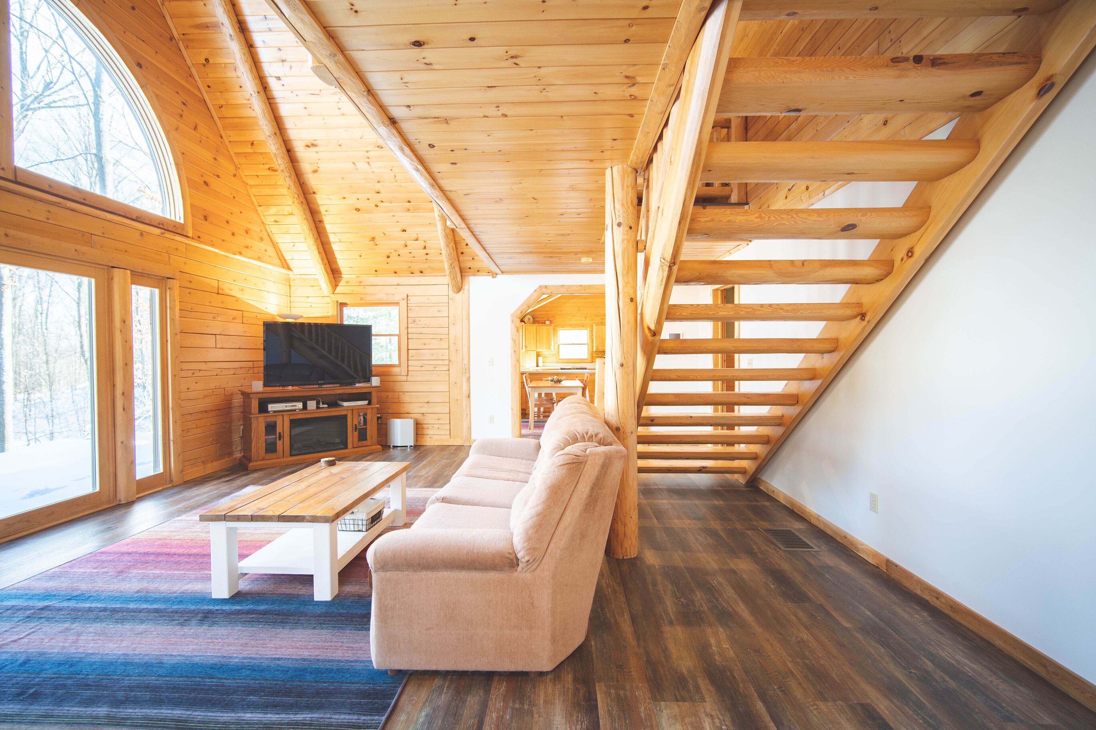Un interior de madera con un sofá, televisor y una escalera.