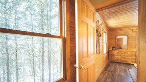 A wooden interior with a large window, wooden cabinets, and a mirror.