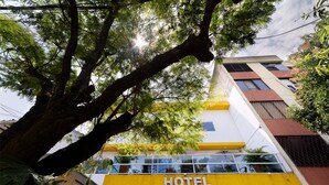 Un hôtel à la façade jaune et blanche, doté de balcons et d’une enseigne indiquant « HÔTEL ».