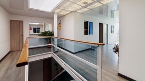 Un intérieur moderne avec une balustrade en verre, un plancher en bois et une verrière.