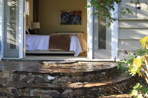 A bedroom with a bed, a painting on the wall, and a stone staircase leading to the room. - CHARMING GARDENS & SUNNY GREAT LOCATION PETS/HOT TUB 
#141214 (Santa Cruz)