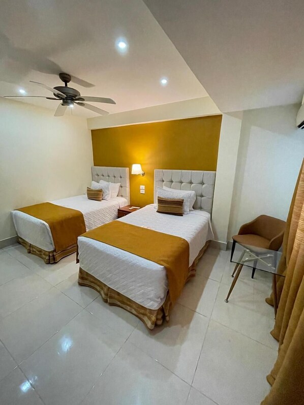 A hotel room with two beds, a ceiling fan, and a small table. - Nilka Hotel Boutique (Samaná)