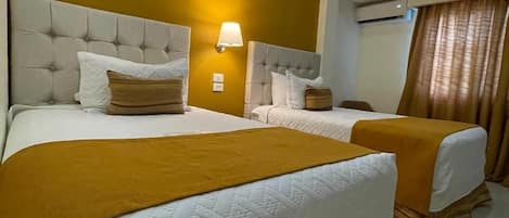 Hotellihuone, jossa on kaksi sänkyä, kattotuuletin ja ilmastointilaite.