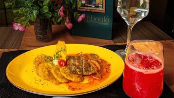 Una mesa de comedor con un plato de comida, un vaso de bebida roja y una botella de agua.