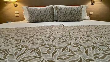 A hotel room with a bed, two wall-mounted lamps, and a patterned bedspread.