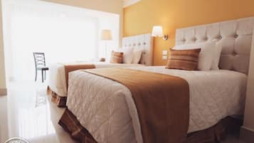 A hotel room with a large bed, a chair, and a lamp.