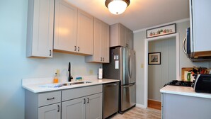 A modern kitchen with light grey cabinets, stainless steel appliances, and a white countertop. - STEPS TO THE SEA AND SAND IN DEWEY BEACH (Dewey Beach)