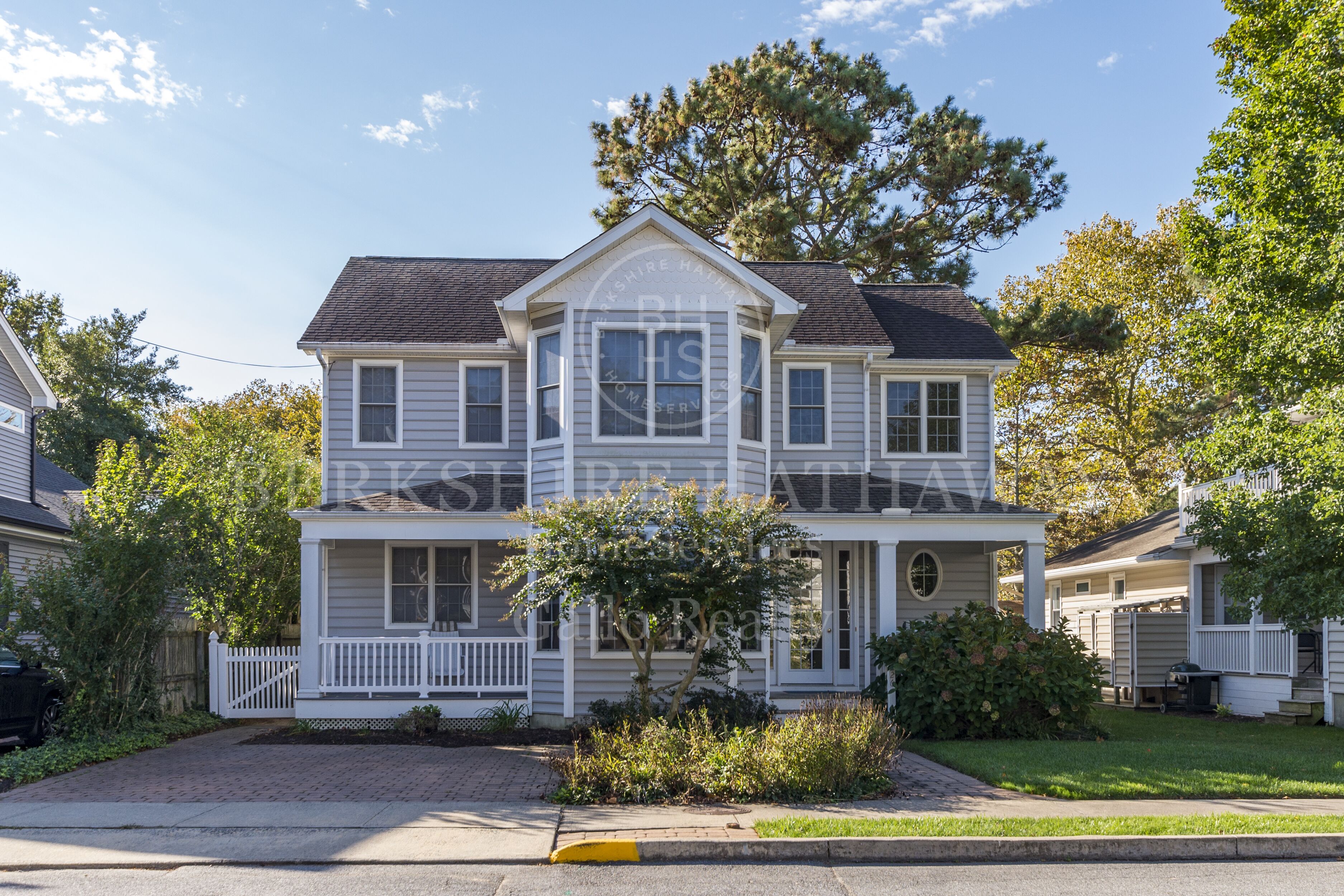 A two-story house with a front porch, a bay window, and a small front yard.