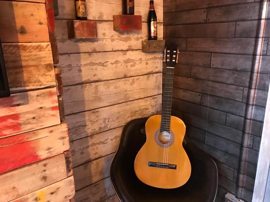 A guitar leaning against a wall with a rustic wooden texture.