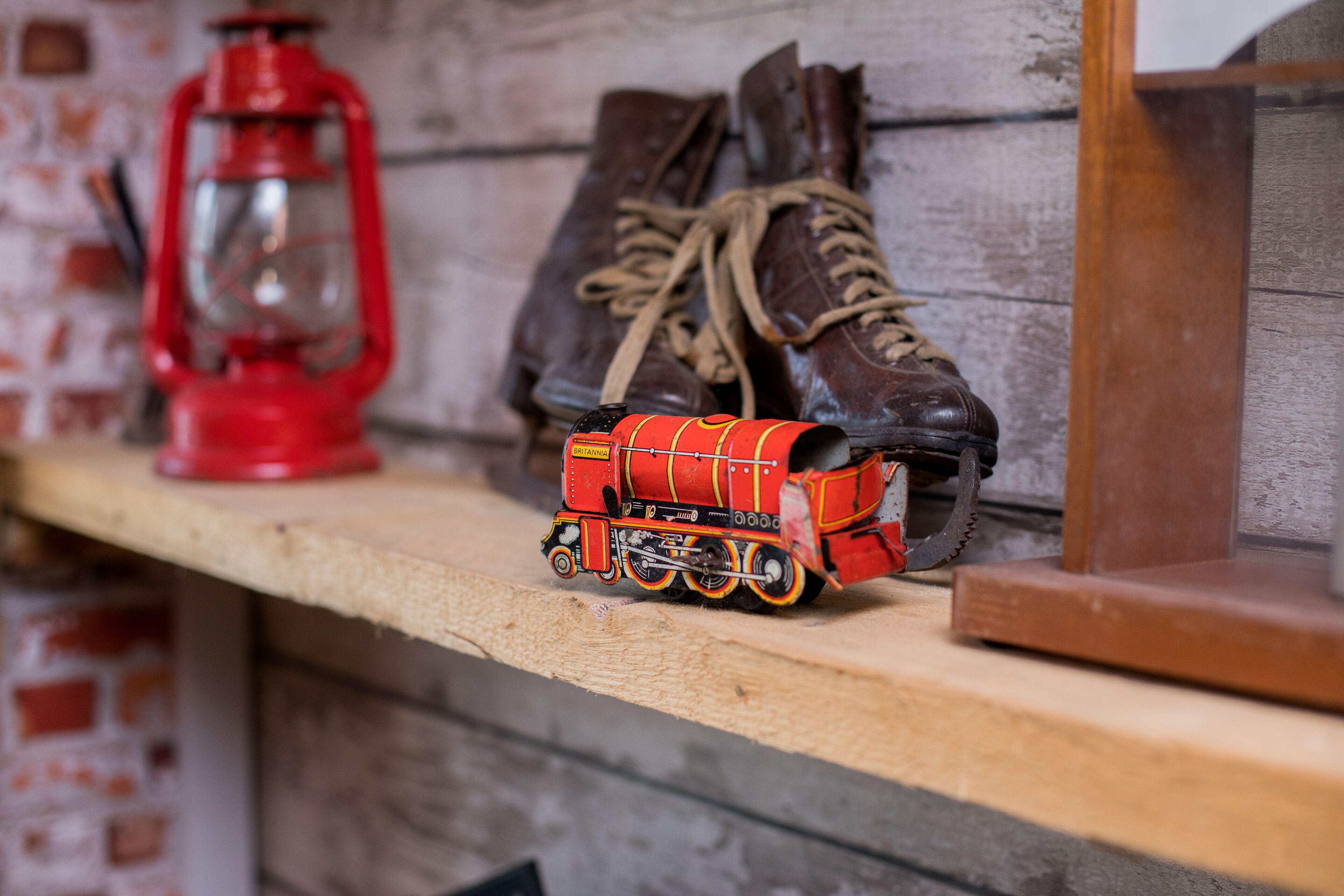 A shelf with a model train, a pair of boots, and a lantern.