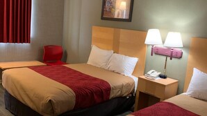 A hotel room with two beds, a red chair, a nightstand with a lamp, and a ceiling-mounted smoke detector. - Falls Inn (Newton Falls)