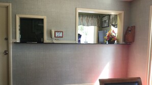 A room with a red carpet, a black leather chair, a shelf with a telephone, a framed picture, and a small plant. - Falls Inn (Newton Falls)