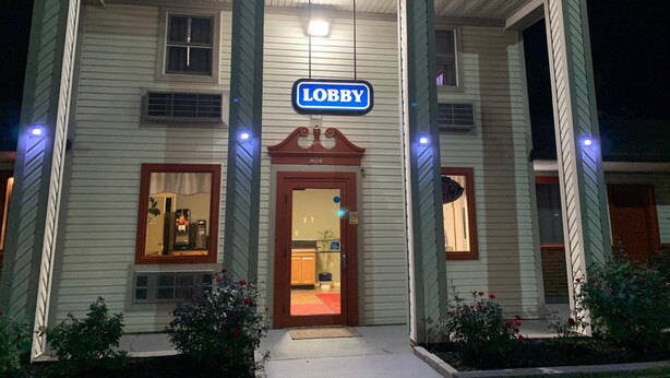 A building with a 'Lobby' sign, a wooden door, and a small window with a plant inside. - Falls Inn (Newton Falls)