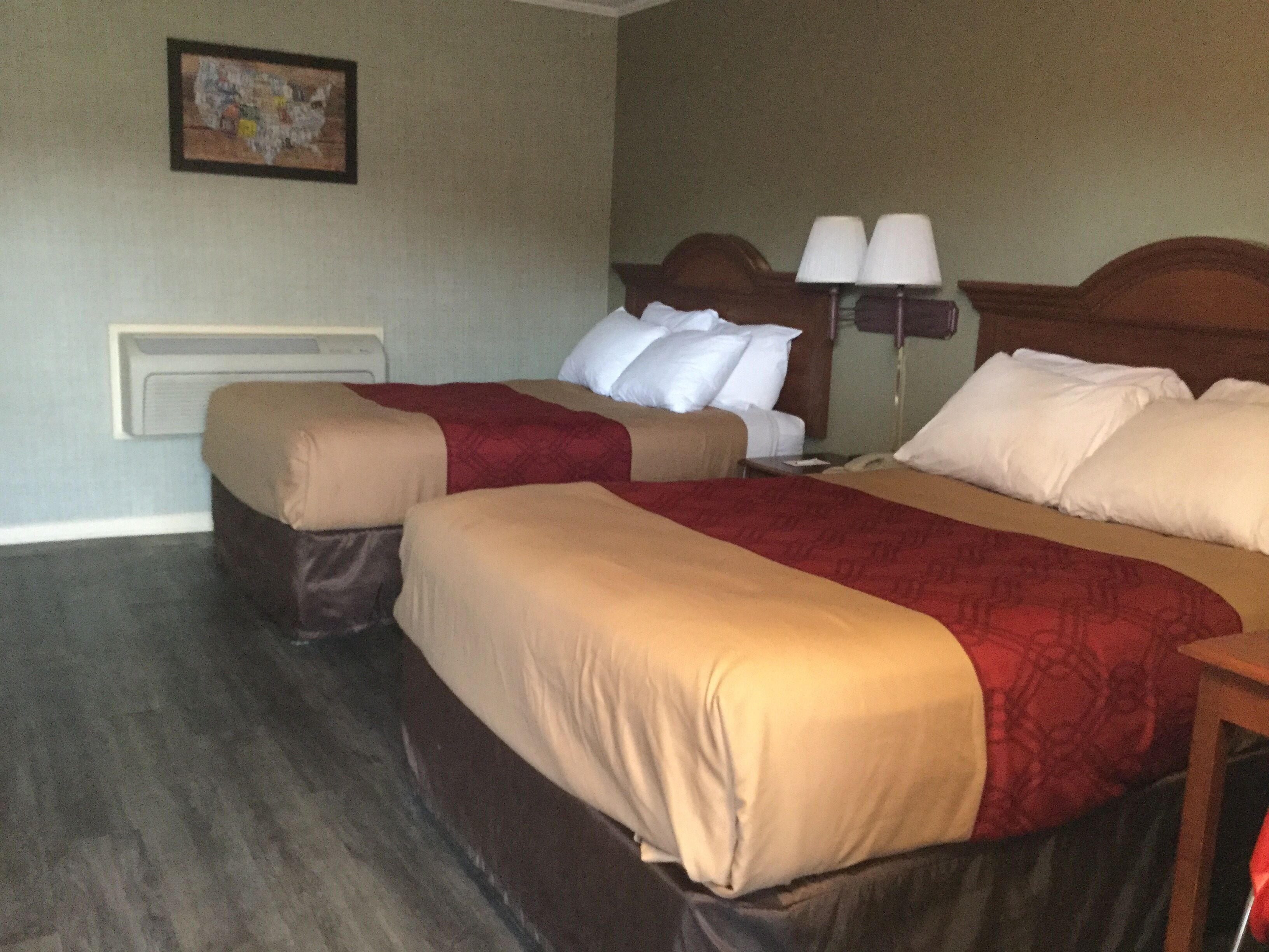 Une chambre d’hôtel avec deux lits, une table de chevet, une lampe et un tableau au mur.