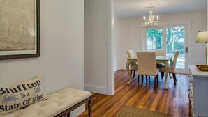 Comedor con candelabro, suelo de madera y vistas al exterior.