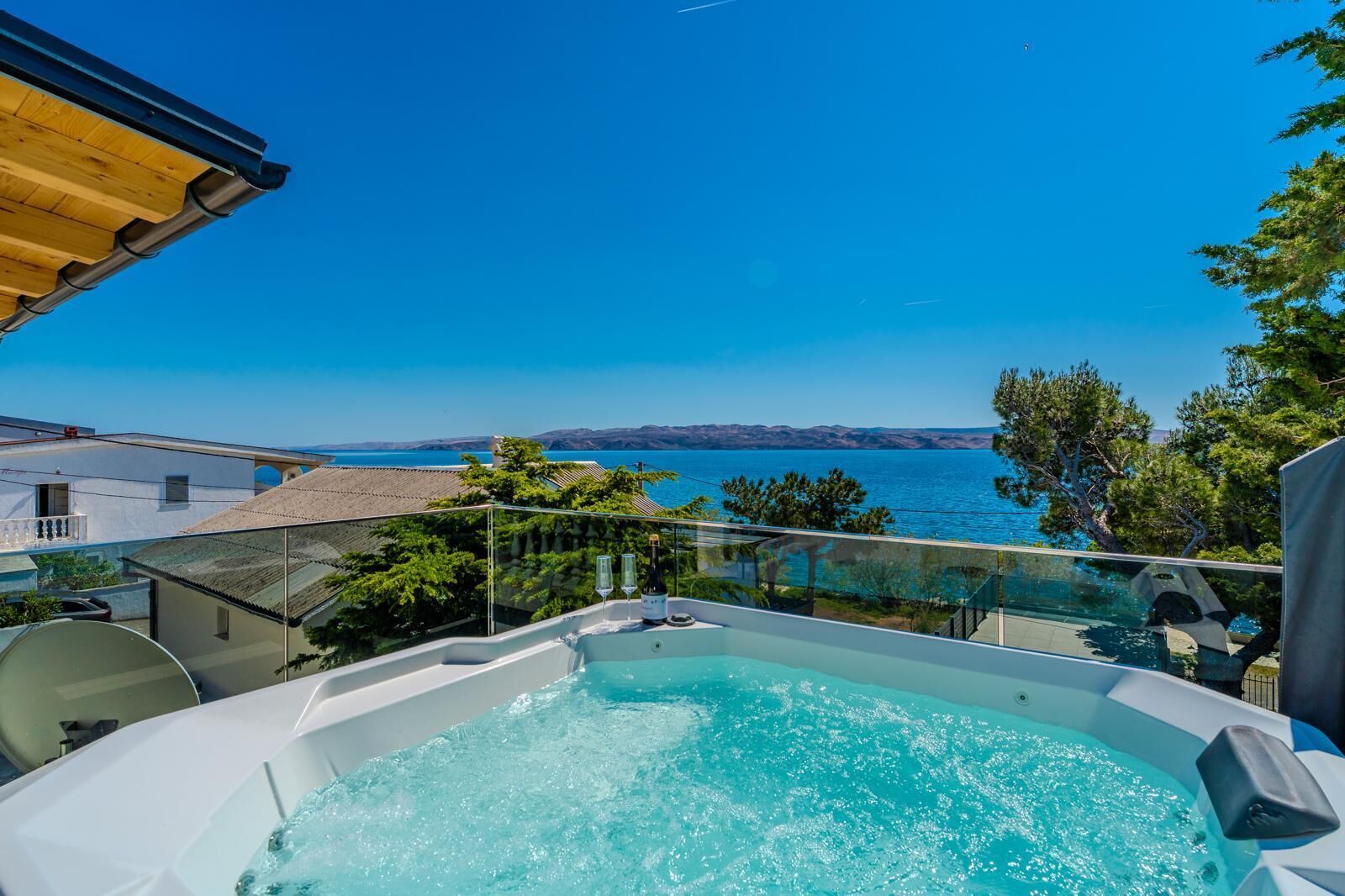 Una vasca idromassaggio su un balcone con vista panoramica sul mare e sulle colline.