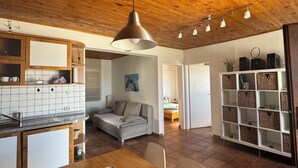 A modern kitchen with wooden cabinets, a dining area with a floral table runner, and a living space with a sofa and a painting. - House Petra on the beach-nice view (Cesarica)