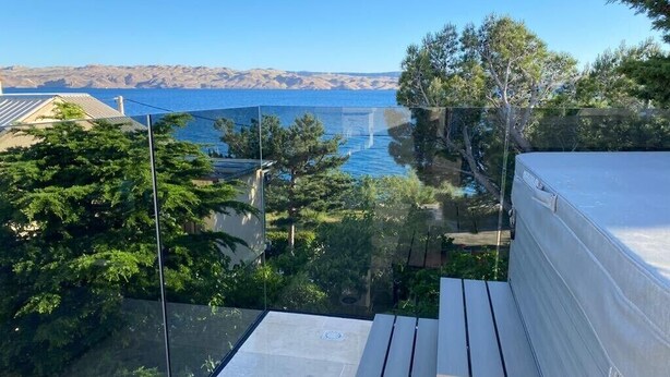 A rooftop terrace with a view of the sea and mountains, a glass balustrade, and a wooden table. - House Petra on the beach-nice view (Cesarica)
