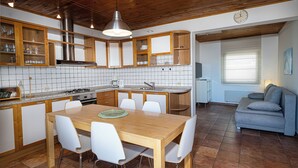 A modern kitchen with wooden cabinets, a dining table, and white chairs. - House Petra on the beach-nice view (Cesarica)