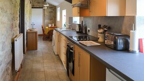 Une cuisine avec des meubles en bois, un plan de travail noir et un mur en pierre.