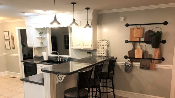 Een keuken met een centraal eiland, barstoelen, hanglampen en een spatwand.