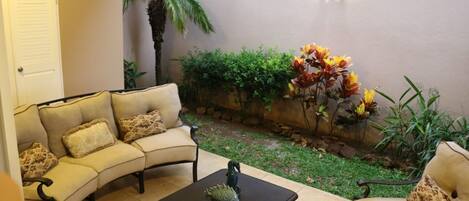 A cozy patio area with a sofa set, a small table, and decorative plants.