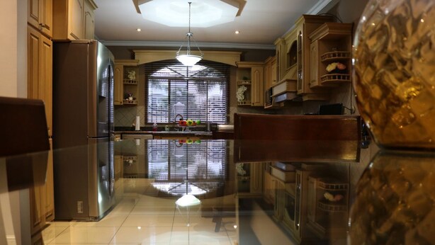 Cozinha moderna com ilha central, eletrodomésticos de aço inoxidável e uma janela grande com persianas.