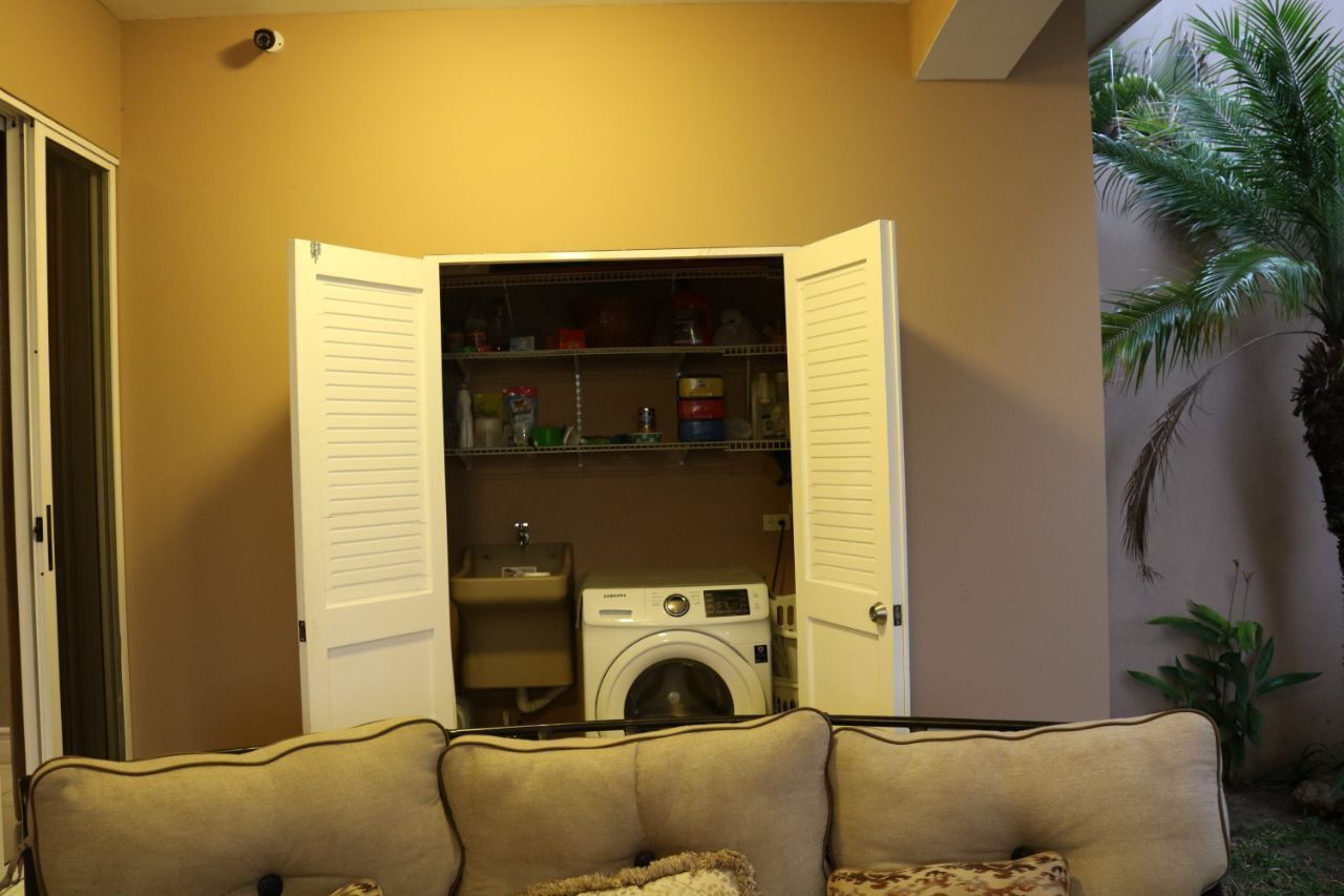 A compact laundry room with a washing machine and shelves of cleaning supplies.