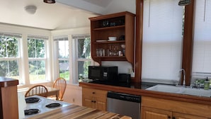 A kitchen with a wooden countertop, a microwave, a dishwasher, and a window with blinds.