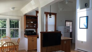 A modern kitchen with wooden cabinets, a microwave, and a dining area with a table and chairs.