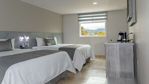 A hotel room with two beds, a small desk, a coffee machine, and a window with a view of the mountains. - Hotel 5 Inn Plus (León)