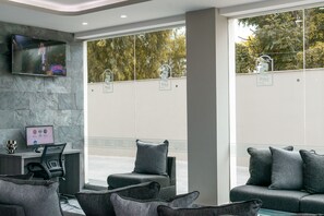 A modern lobby with a reception desk, seating area, and large windows. - Hotel 5 Inn Plus (León)