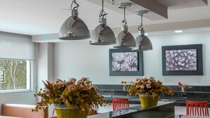 A modern dining area with a long table, red chairs, and decorative vases with flowers. - Hotel 5 Inn Plus (León)