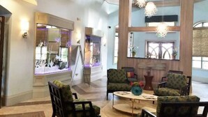 A spacious lobby with a high ceiling, large windows, and modern furniture.