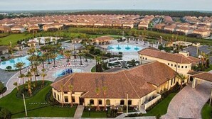 A resort with multiple swimming pools, a central courtyard, and a large building with a tiled roof.