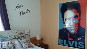 Un dormitorio con una cama, un cartel de Elvis Presley y una pared con los nombres 'Elvis' y 'Dresley'.