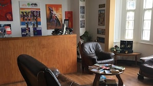 Un área de descanso con sillones de cuero, una mesa de centro de madera y un mostrador de recepción con diversos objetos exhibidos.