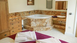 Ein Badezimmer mit einer freistehenden Badewanne, einem Holzkabinet, einer Marmorarbeitsplatte und einem Handtuch auf dem Boden.