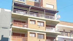 A multi-story residential building with balconies, a garage, and a small storefront at the ground level.