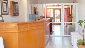 A spacious living area with a wooden central island, a kitchen with a stove and sink, and a sliding glass door leading to a dining area.