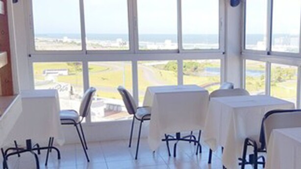 A room with large windows, white tables, and chairs.