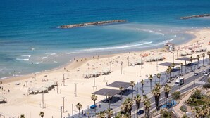 Uma praia com uma torre salva-vidas, guarda-sóis e palmeiras.