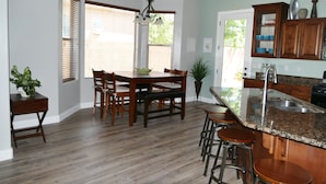 A modern kitchen with a dining area, wooden flooring, and a granite countertop. - Private Home & Fenced POOL 32'x16', sleeps 15, Jacuzzi,  TV/Game rm, Play-Set (La Verkin)