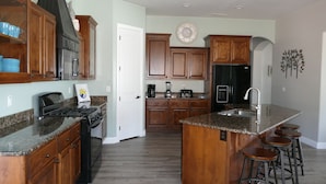 A kitchen with wooden cabinets, a granite countertop, a stainless steel refrigerator, and a sink. - Private Home & Fenced POOL 32'x16', sleeps 15, Jacuzzi,  TV/Game rm, Play-Set (La Verkin)