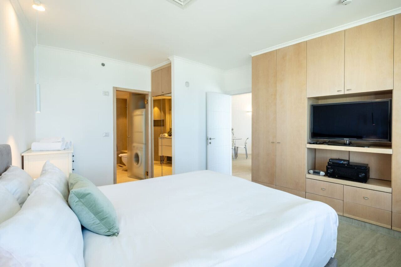 Ein Hotelzimmer mit einem großen Bett, einem Fernseher und einem Kleiderschrank.