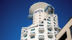 Un hotel alto con un remate cilíndrico, balcones y un cartel que dice 'Sea Tower Hotel Design'.