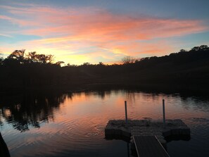 Un lac paisible au coucher du soleil, avec une jetée qui s’avance dans l’eau.