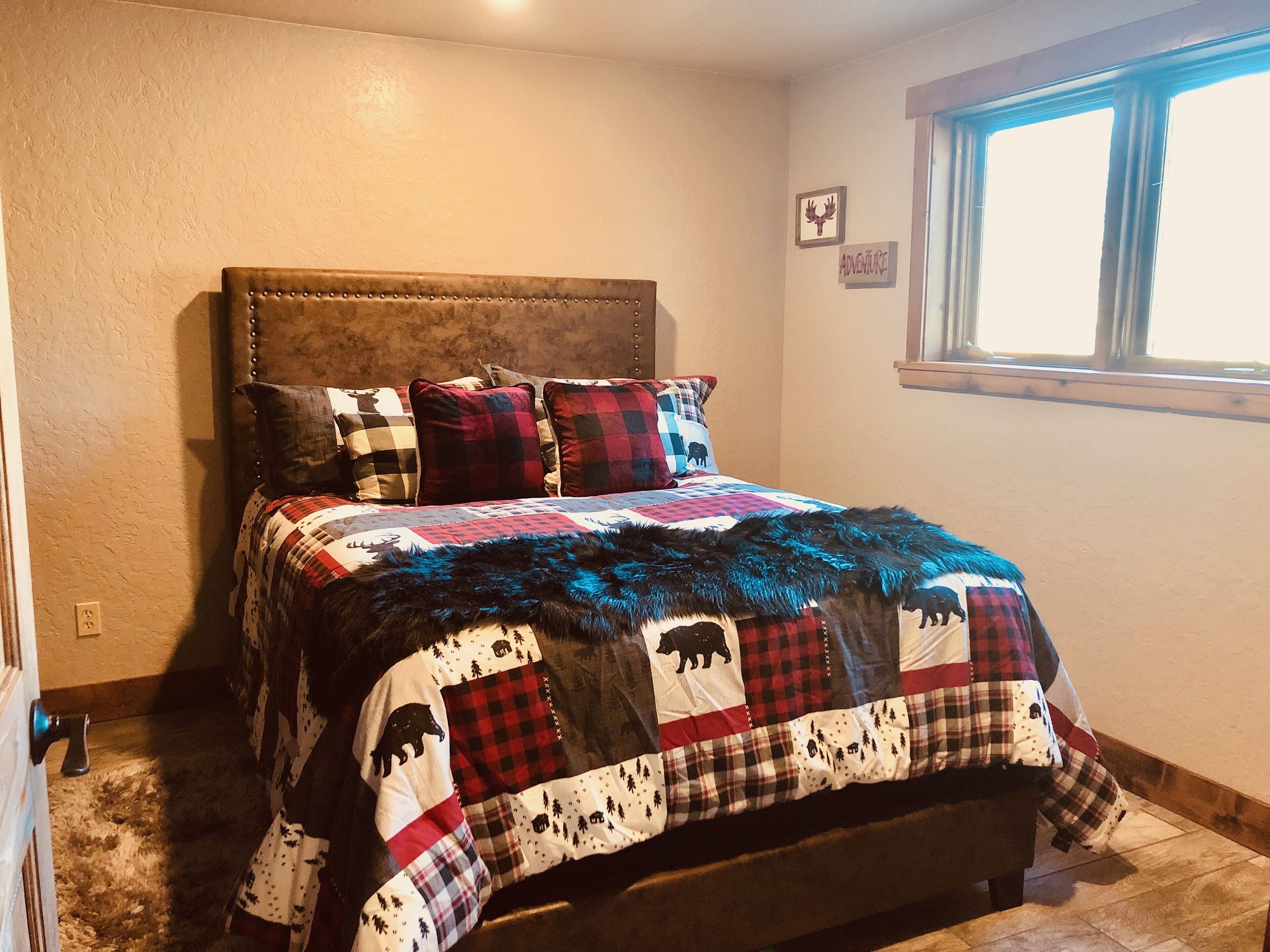 Ein Schlafzimmer mit Bett, Fenster und einer Wand mit einem Bilderrahmen.