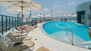 A rooftop pool with sun loungers, umbrellas, and a clear view of the cityscape. - Luxurious 90sqm 2BR Beach Front (Tel Aviv)